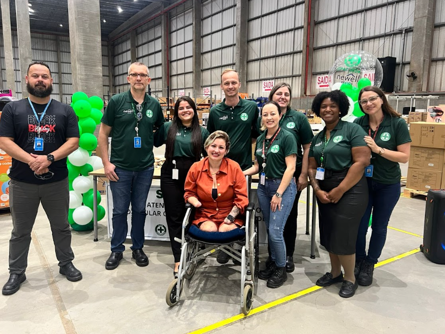 Silvana cercada pela equipe durante visita corporativa em galpão